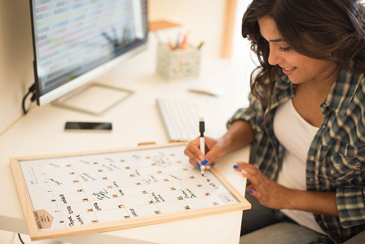 Recruiting ideas for warehouse workers: Woman on computer desk writing on a calendar.