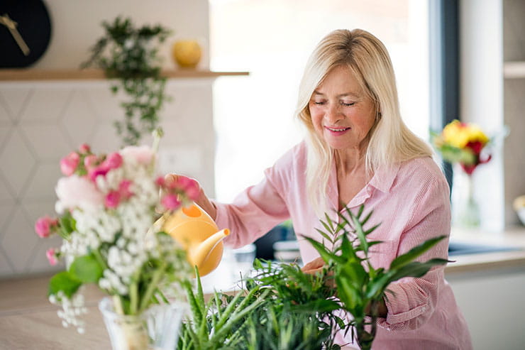 Woman watering houseplants with watering can